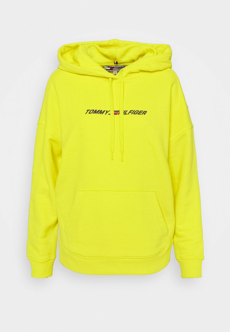 Sweat à capuche jaune néon avec une grande poche avant, des manches longues et un cordon de serrage réglable. Présente le logo "TOMMY HILFIGER" en noir. Texture douce.