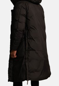 Czarna kurtka puchowa z kapturem, o długim kroju, z prążkowanymi mankietami i bocznymi zamkami, wykonana z gładkiej, teksturowanej tkaniny zewnętrznej.