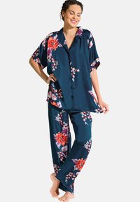 Navy bloemen pyjama set van satijnstof; kortom mouwige knoopsluiting shirt met grote bloemen en wijde broek met een vergelijkbaar patroon.
