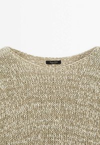 Pull en maille beige clair avec un col lâche et large, présentant un fil texturé et un motif chiné subtil. Étiquette cousue à l'intérieur.