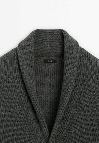 Cardigan en maille côtelée gris foncé avec un col châle épais, présentant une texture détaillée et une étiquette de marque à l'intérieur de l'encolure.