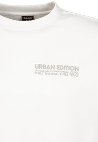 Weißes Baumwoll-T-Shirt mit Rundhalsausschnitt, das auffälligen grauen Text zeigt: "URBAN EDITION THE SUBLEVEL CLOTHING BRAND ONLY THE REAL ONES" auf der Vorderseite.