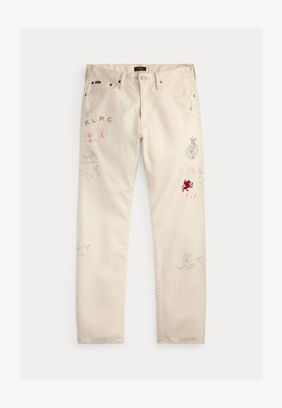 Off-white bukser med flere små, falmede og røde trykte logoer, tekst og symboler spredt på forsiden av ben og lommer.