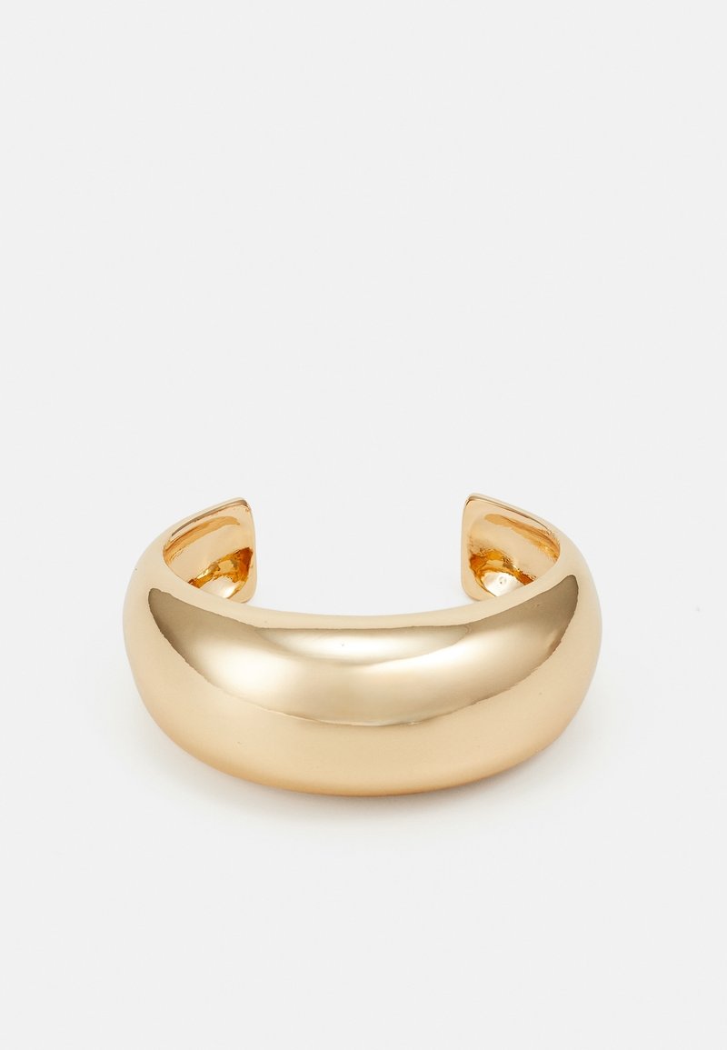 Bracelet manchette en or brillant et épais avec des bords lisses et arrondis sur un fond blanc, ouvert aux extrémités pour être placé autour du poignet.