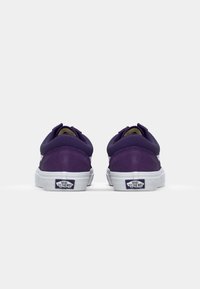 Purple suede sneakers with white rubber soles, featuring a padded collar and prominent logo on the heel. Rounded shape with minimal design.