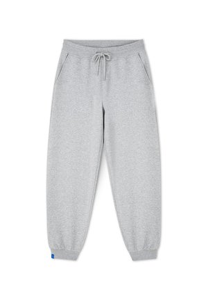 Szare bawełniane spodnie dresowe z elastycznym pasem, regulowanym sznurkiem, bocznymi kieszeniami i dopasowanymi mankietami. Na dole znajduje się niebieska metka.
