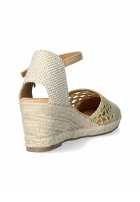 Sandalia cuña con tejido trenzado en beige y tacón de yute trenzado de color claro. Cuenta con una correa en el tobillo y un diseño recortado en la parte delantera.