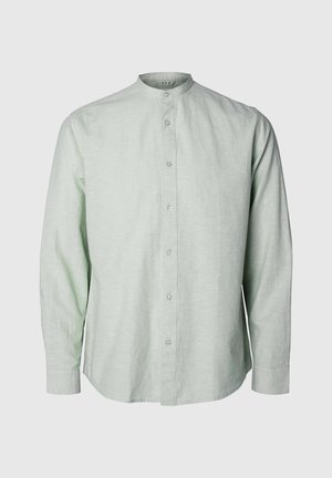 Vihreä pellavapaita, jossa on kauluksen ympärys, pitkät hihat ja napitus edessä. Kangas näyttää teksturoidulta ja hengittävältä.