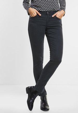 Zwarte slim-fit jeans met een gladde textuur en vijf pocket ontwerp, gecombineerd met een blouse met een print en zwarte enkelboots.
