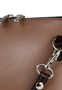 Bruine synthetische handtas met een gladde textuur, zilveren beslag en een afneembare donkerbruine riem met stikseldetails.