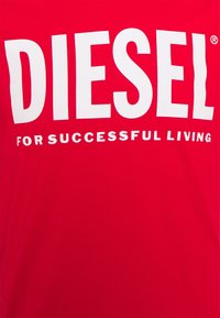 Camiseta de algodón roja con gran texto blanco, "DIESEL," y texto más pequeño, "PARA UNA VIDA EXITOSA," centrado en la parte delantera.