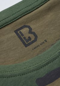 Grønn camo bomull T-skjorte med merkelapp som viser størrelse "Dame størrelse S" med svart logo og brodert halslinning for holdbarhet og komfort.