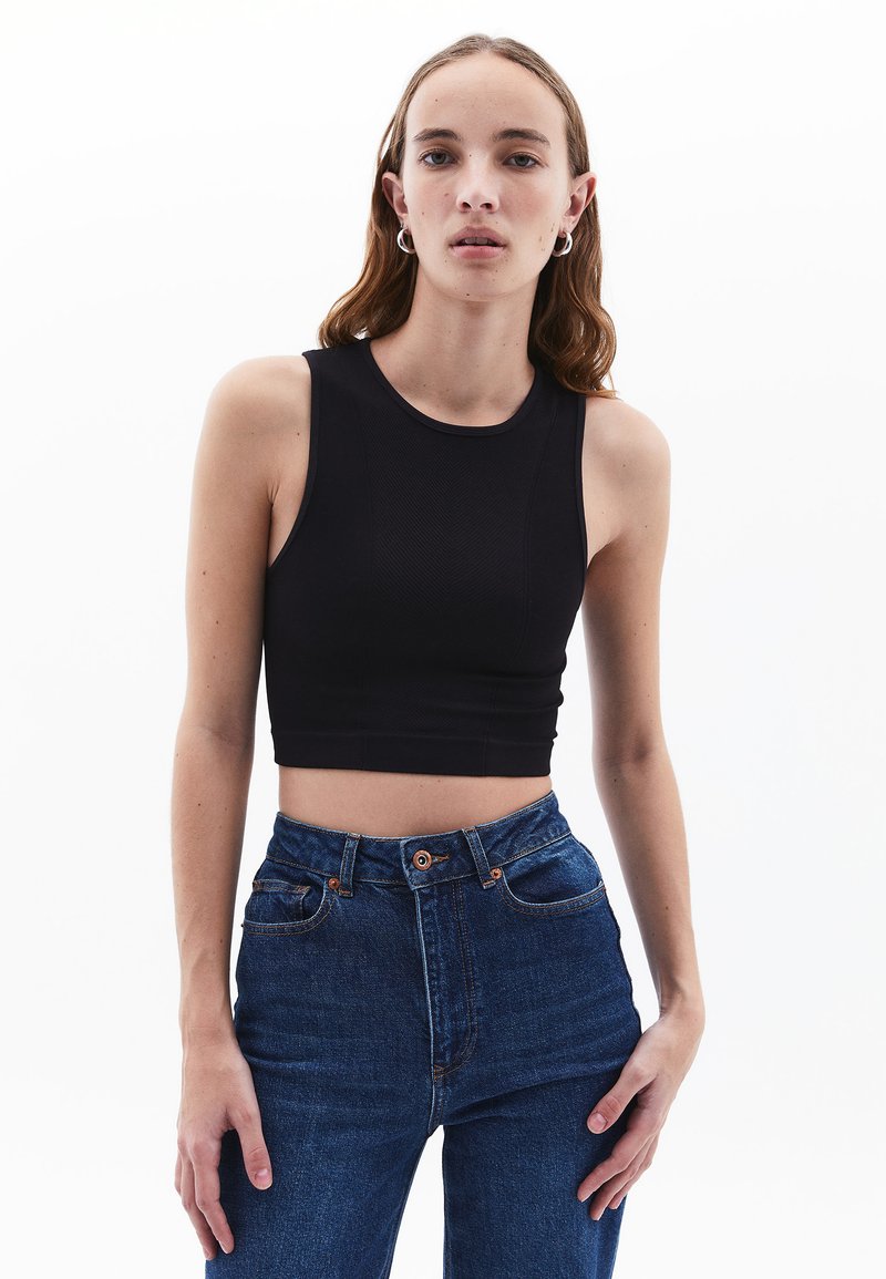 Top corto nero con scollo a giro e spalline larghe, abbinato a jeans in denim blu a vita alta. Tessuto morbido e design aderente.