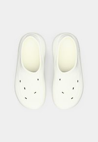 Balti slip-on apavi ar gludu tekstūru, noapaļotu formu un ventilācijas atverēm. Minimālisma dizains ar diskrētu zīmolu sānos.