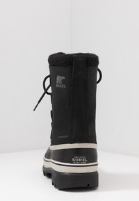 Schwarzer Gummistiefel mit Kunstfellfutter, Schnürdesign und verstärkten Nähten. Verfügt über eine strukturierte Sohle und ein Markenlogo an der Seite.