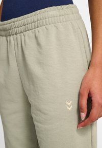 Ljusgröna bomullsbyxor med elastisk midja. Har en blekbeige chevronbroderi på vänster lår. Slät textur, avslappnad passform.