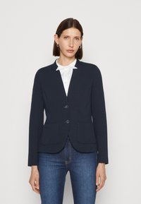 Blazer blu navy con un design strutturato, due tasche frontali, colletto a intaglio e due bottoni, realizzato in tessuto testurizzato.