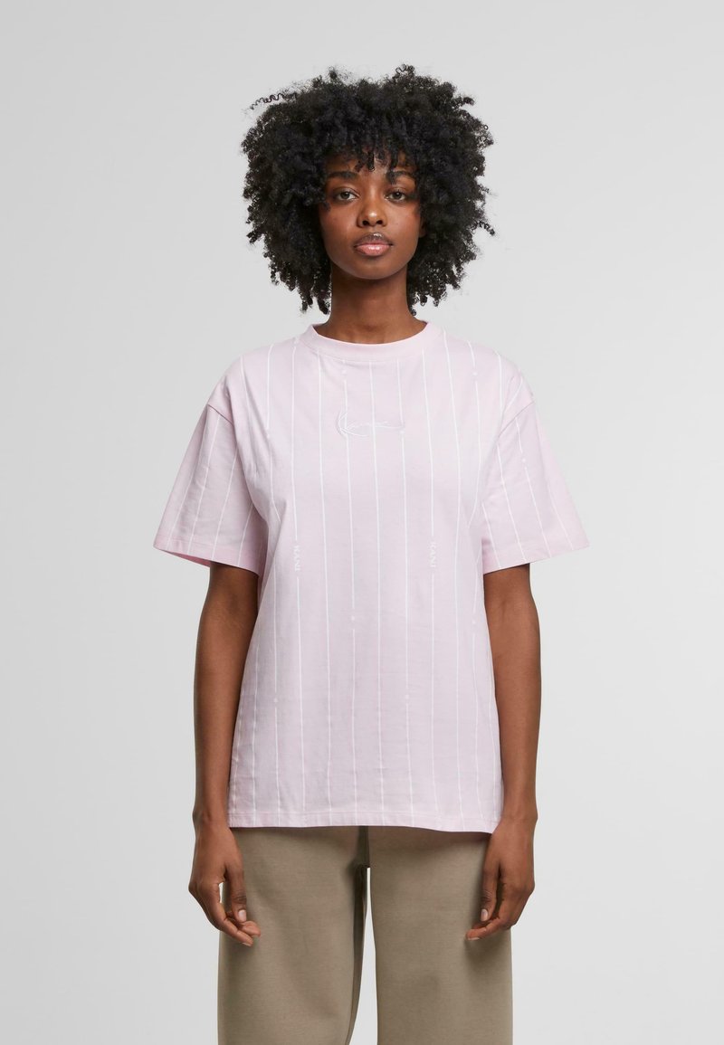 Camiseta de talla grande en color rosa claro, hecha de algodón, con rayas verticales blancas y un pequeño logotipo en el pecho. Diseñada con mangas cortas y cuello redondo.