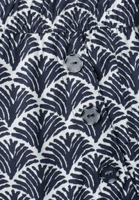 Black and white fabric with abstract leaf pattern and three shiny black two-hole buttons in a vertical row.