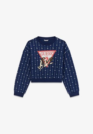 Temno modra skrajšana majica z dolgimi rokavi z vzorci ponavljajočih se geometrijskih oblik, ki vključuje rdeč trikotni logotip s besedilom "GUESS U.S.A." in zlatim poudarkom "love".