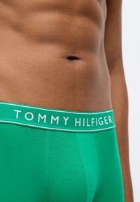 Zöld pamut boxer alsónadrág fehér logós derékkal. Az anyag simának tűnik, fitted kialakítással és látható varrási részletekkel rendelkezik.