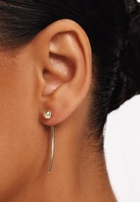 Gouden metalen oorbellen met een bolvormige studs en een gebogen hangend ontwerp. Het hangdeel is glad en dun, wat zorgt voor een moderne uitstraling.