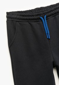 Sorte sweatpants med en struktureret finish, der har en elastisk talje, to sidelommer og kontrasterende blå snore.