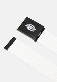 Witte geweven stoffen riem met een zwarte metalen gesp met een logo. De gesp heeft een gladde oppervlakte en een rechthoekige vorm.