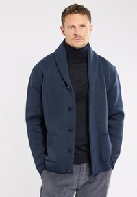 Cardigan tricot marine avec un col châle, fermeture à cinq boutons et deux poches avant ; tissu texturé avec un motif subtil.