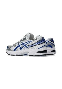 Atletické boty z bílé síťoviny s modrými a stříbrnými akcenty, se strukturovaným designem a pevným černým gumovým podešví.