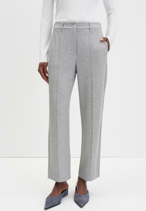 Graue weit geschnittene Hose aus strukturiertem Stoff, mit Knopfverschluss, seitlichen Taschen und taillierter Passform, kombiniert mit spitzen grauen Schuhen.