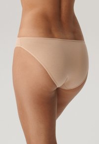 Beżowa bielizna bikini z mieszanki bawełny o gładkiej fakturze, niskim kroju i minimalnych szwach, z bezszwowym tyłem i lekkim rozciągnięciem.