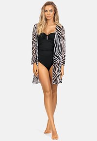 Czarny kostium kąpielowy z marszczonym wzorem, podkreślony dekoracyjnym zapięciem, zestawiony z przezroczystym kimono w paski zebry z szerokimi rękawami.