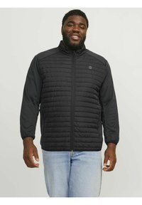Sort jakke med quiltet sektion foran, lange ærmer, lynlås åbning og logo detaljer. Casual design parret med lyse denim jeans.