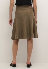 Bruine, knie-lange, uitlopende rok van textiel met een hoge tailleband en zijsplitsen, gecombineerd met zwarte blokhak sandalen.