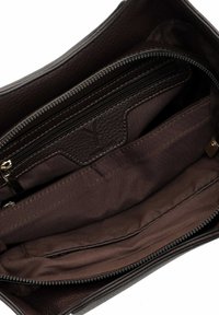 Pruuni tekstuuriga nahast käekott, mille sisemus sisaldab mitmeid sektsioone, sealhulgas lukuga taskut ja tumedat pruunist kangast voodrit.