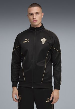 Svart zip-up träningsjacka med guld accenter, som har en logo och varumärkesnamn på bröstet, tillverkad av ett slätt, lätt material.