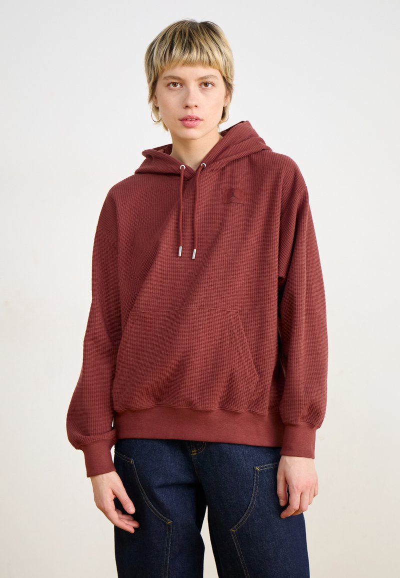 Sudadera con capucha color burdeos de textura gofre, con bolsillo frontal y cordón ajustable. Puños y dobladillo acanalados, con un pequeño logotipo.
