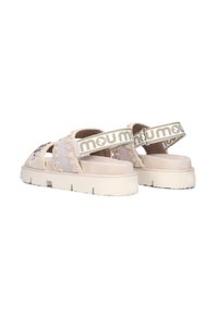 Sandali beige in suede con dettagli intrecciati, design a fascia larga, suola bianca spessa e cinturini alla caviglia con il marchio "mou" in lettere bold.