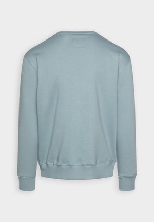 Ljusblå sweatshirt med rund halsringning, ribbade ärmslut och fåll. Slen textur med en liten etikett bak.