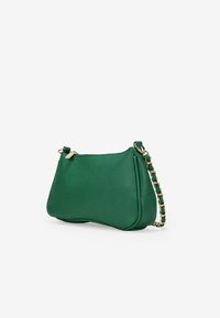 Bolso de piel verde con una textura suave, forma curvada y correa de cadena dorada. Presenta un cierre con cremallera y un diseño minimalista.