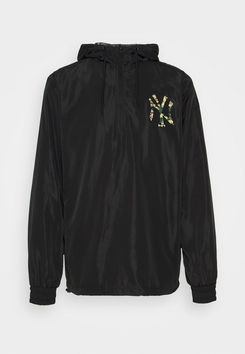 Coupe-vent noir avec capuche, fermeture à glissière sur le devant jusqu'à mi-hauteur, poignets elastiques et logo New York Yankees à motif camouflage vert sur la poitrine.