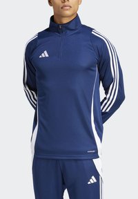 Marineblaue sportliche Viertelzip-Oberbekleidung aus glattem Stoff, mit weißen Seitenstreifen und einem Adidas-Logo auf der Brust und der Hose.