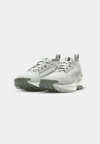Light gray athletic shoes with a textured upper, rubber outsole, and white accents. Features lacing system and pull tabs on the heel.