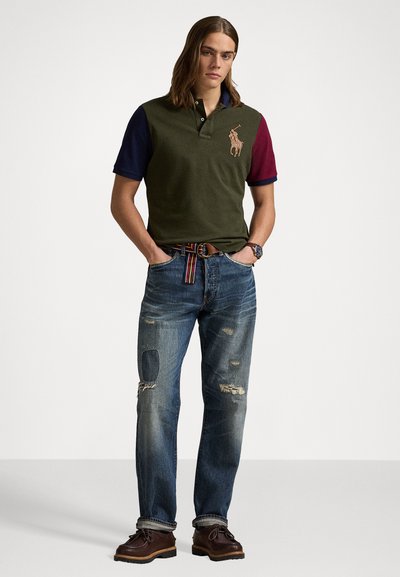 Polo shirt in olijfgroen, marineblauw en bordeauxrood, met een geborduurd logo. Gemaakt met versleten blauwe jeans en bruine veterschoenen.