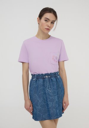T-shirt di cotone viola con tasca e testo e grafica "HUG me". Gonna in denim blu con motivi bianchi a mano e vita elasticizzata.