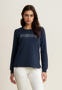 Sudadera de manga larga azul marino hecha de un tejido suave, con un logotipo texturizado "FREDDY" en rhinestones en la parte delantera y un corte relajado.