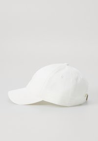 Hvid baseballcap lavet af bomuld med en buet skygge, der har ventilationshuller og en metalbuckle-lukning bagpå.