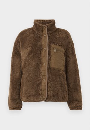 Brown fleece jacket with a high collar, featuring a quilted chest pocket and snap closures along the front. Soft, textured fabric.