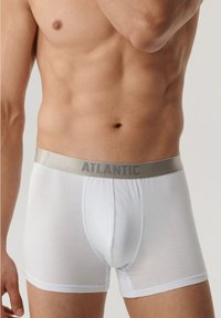 Białe bawełniane bokserki z miękkim szarym pasem z napisem "ATLANTIC". Gładka tekstura, dopasowany krój i długość do połowy uda.